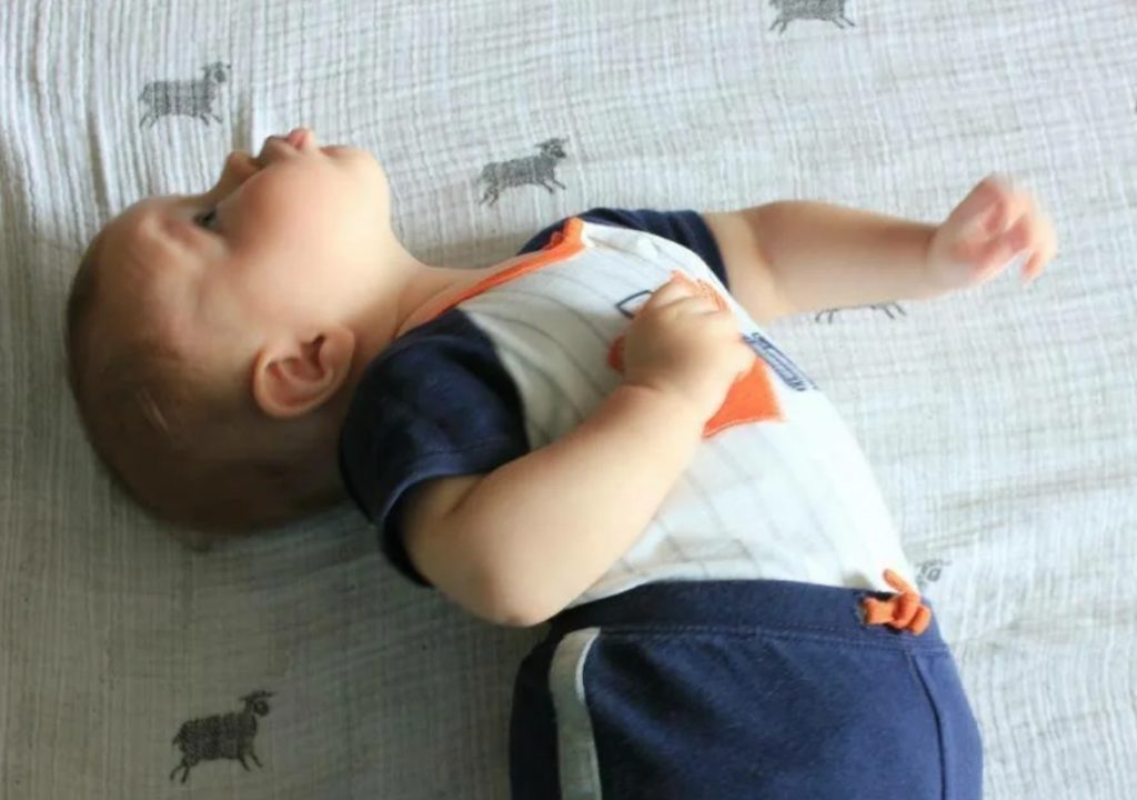Почему новорожденный запрокидывает. Ребенок запрокидывает голову назад. Запрокидывание головы у ребенка. Ребенок лежит.